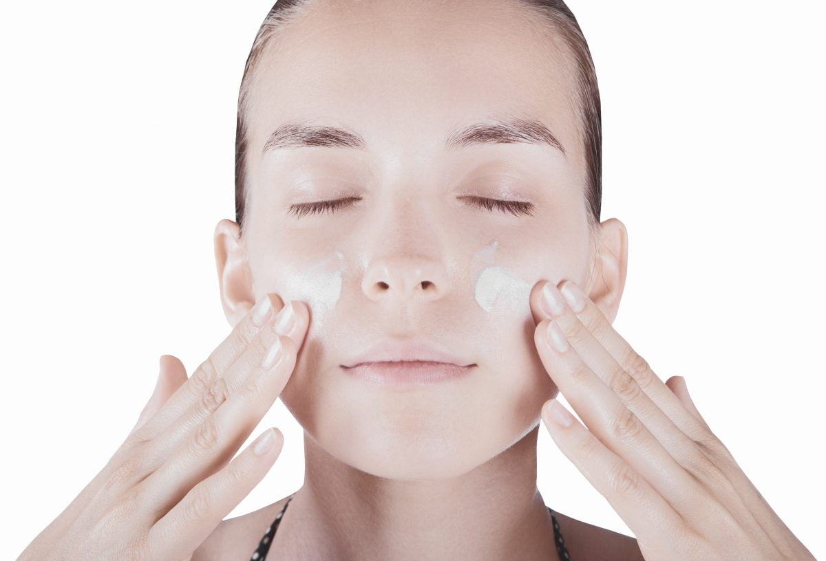 Viso donna con crema spalmata sfondo bianco